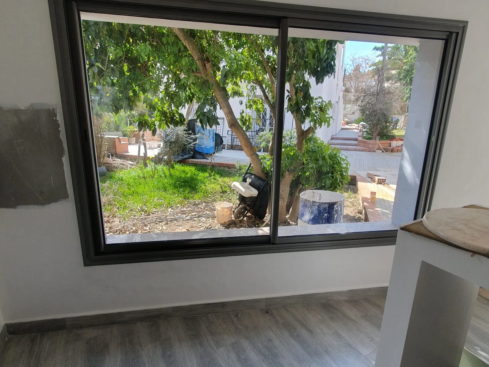 Fenêtre coulissante en aluminium posée par Metralf, vue sur un jardin
