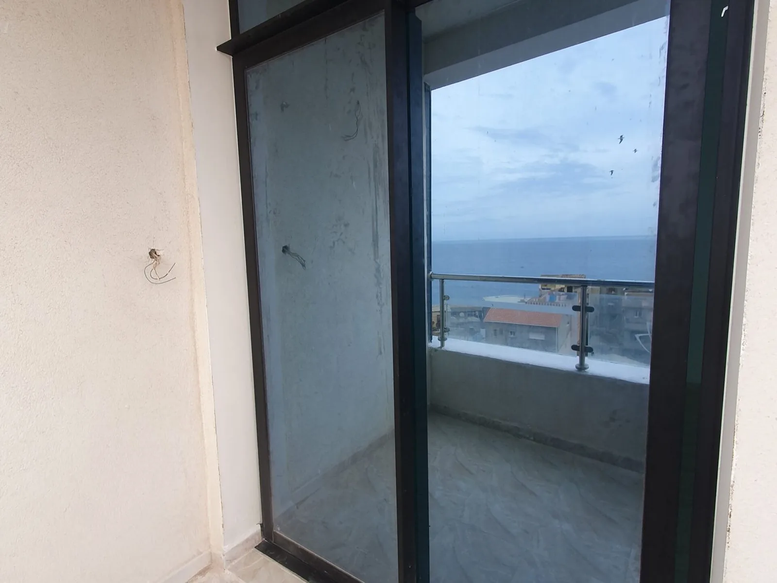 Porte-fenêtre coulissante en aluminium posée par Metralf, vantail ouvert sur une terrasse et la mer